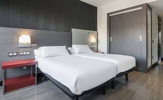 Hotellihuone, jossa on sänky, yöpöydät ja vaatekaappi.