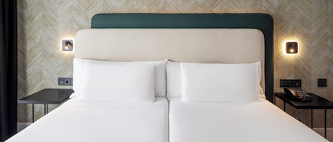 Una cama doble con cabecera verde, dos mesitas de noche y dos luces fijadas a la pared.