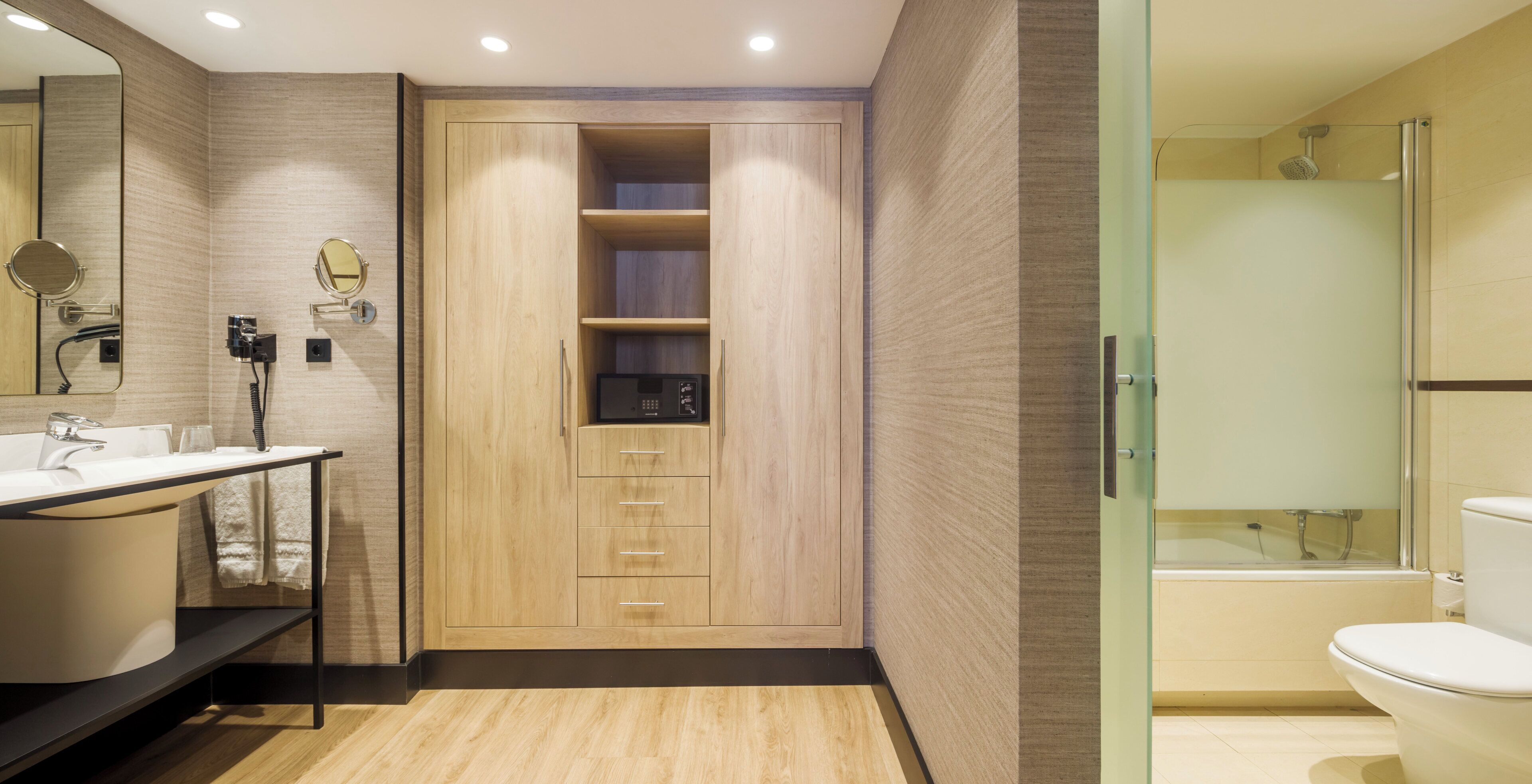 Une salle de bain moderne avec un meuble-lavabo en bois, une cabine de douche en verre et un meuble de rangement intégré.