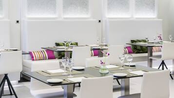 A modern dining area with tables set for two, white chairs, and a green vase with flowers.