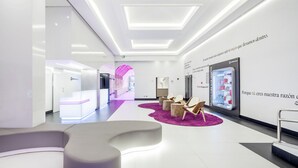 A modern lobby with a reception desk, seating area, and a large digital display. - Hotel ILUNION Suites Madrid (Madrid)