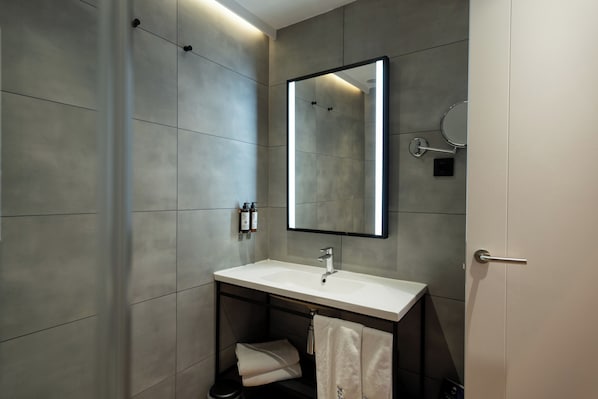 A modern bathroom with a large mirror, a sink, and a towel rack. - Petit Palace Cliper Gran Vía (Madrid)