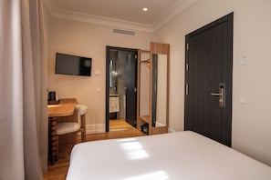 A hotel room with a bed, a desk, a chair, a television, and a wardrobe. - Petit Palace Cliper Gran Vía (Madrid)