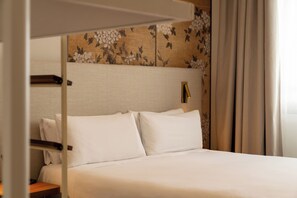 A hotel room with a bed, a headboard with a floral pattern, a bedside table, and a curtain. - Petit Palace Cliper Gran Vía (Madrid)