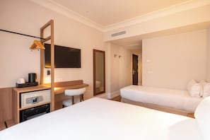 A hotel room with a bed, a desk with a flat-screen TV, a mirror, a small stool, and a wardrobe. - Petit Palace Cliper Gran Vía (Madrid)