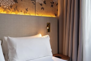 A hotel room with a bed, a nightstand, a wall-mounted light, and a curtain. - Petit Palace Cliper Gran Vía (Madrid)