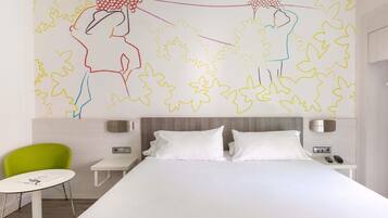 Habitación de hotel moderna con una cama grande, una silla verde, una mesita pequeña y una pared con arte abstracto.