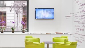 Un interior moderno con un ventanal grande, un televisor de pantalla plana y sillas de color amarillo brillante.