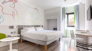 Una habitación de hotel moderna con cama, mesita de noche y escritorio con sillas.