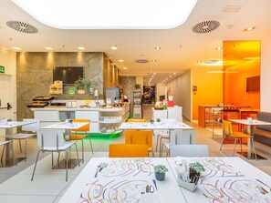 Un restaurante moderno con una barra central, zona de estar y un interior luminoso y bien iluminado.