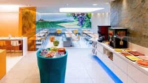 Un comedor moderno con bufé, disposición de mesas y sillas, y un mural en la pared.