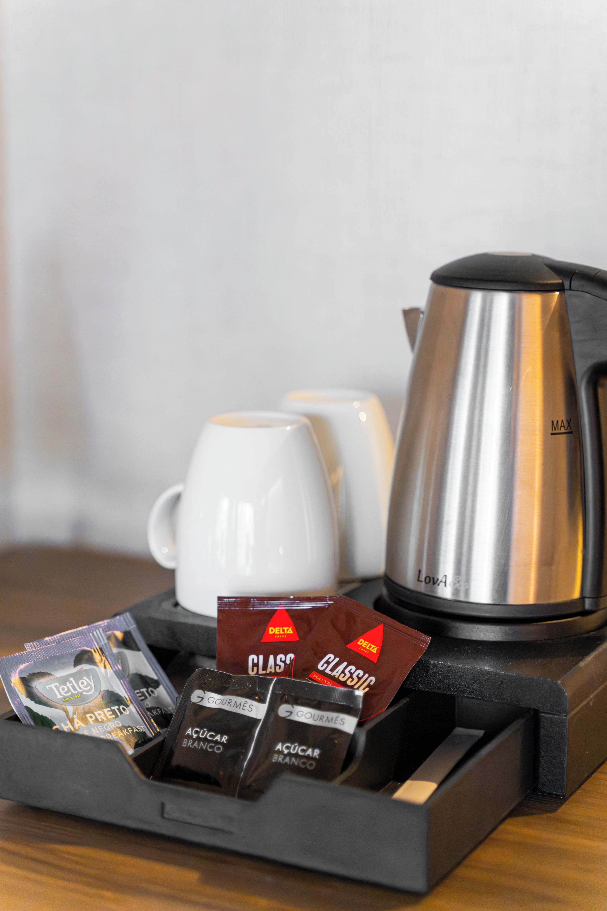 Een koffie-set met een koffiekan, twee witte kopjes, en een dienblad met koffiezakjes en een doosje met de tekst 'CLASSIC'.