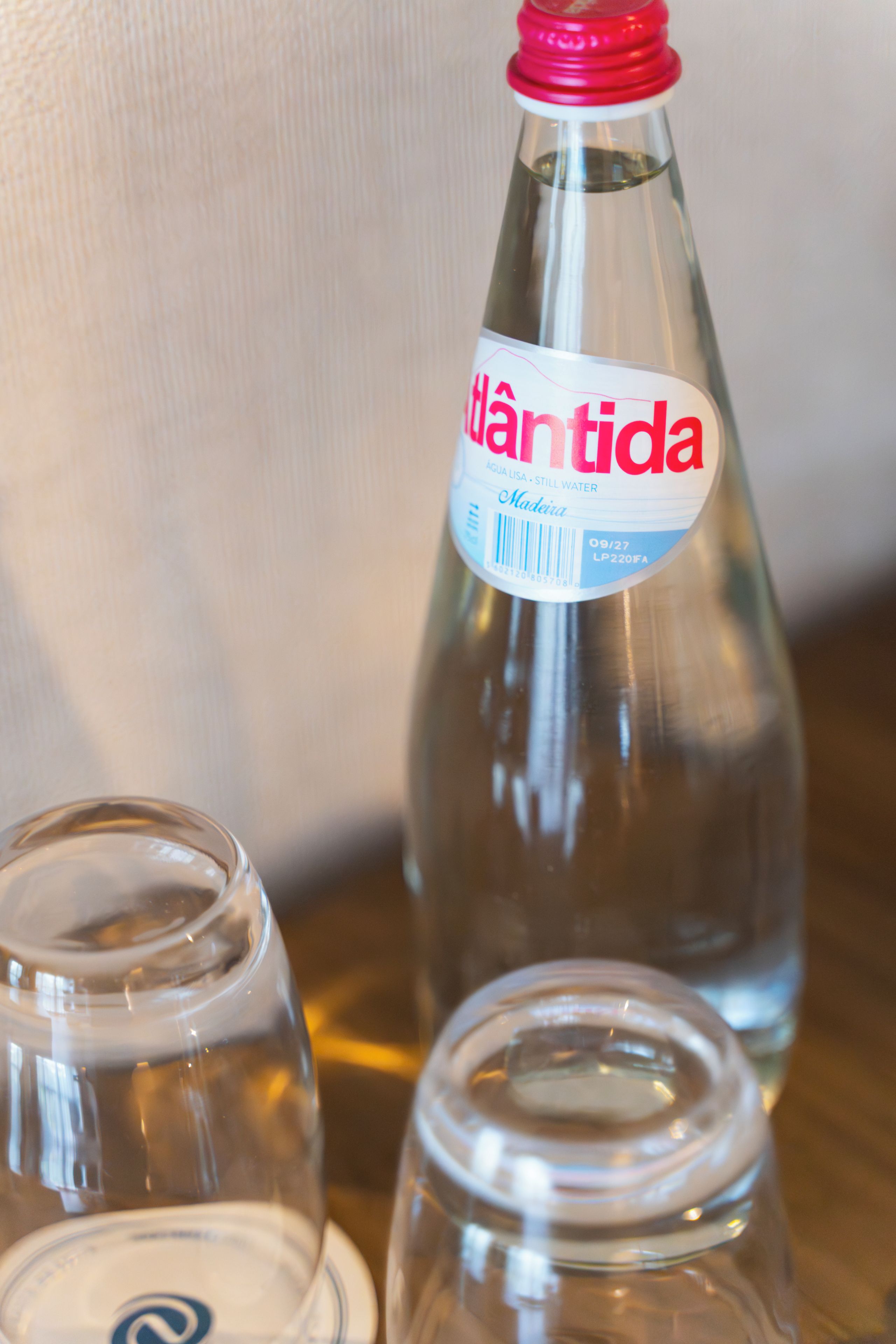Une bouteille en verre transparent avec un bouchon rouge et une étiquette indiquant le nom « Hântida », ainsi qu’une mention précisant qu’il s’agit d’eau de source.