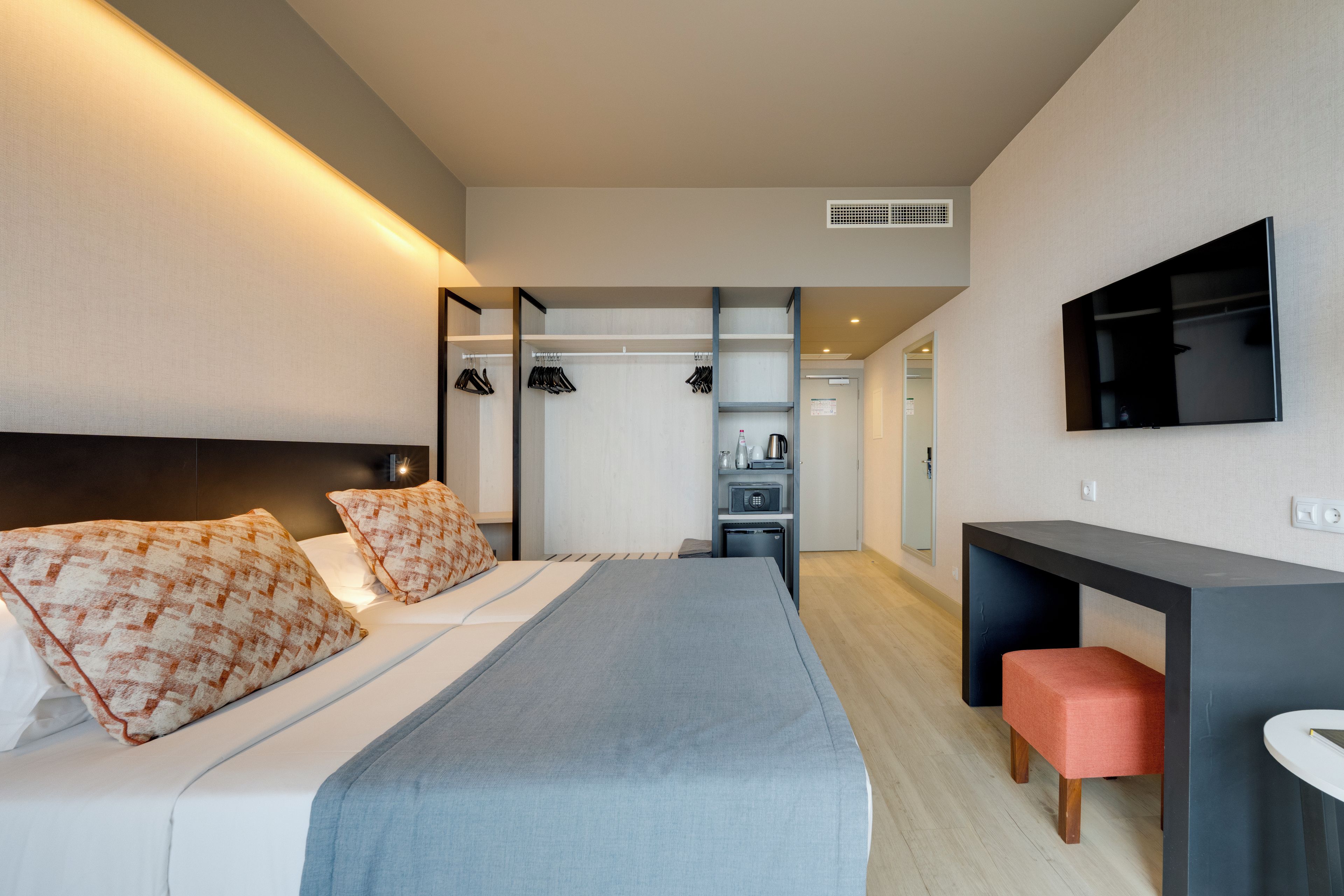 Una habitación de hotel moderna con cama, escritorio y televisor.