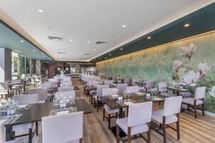 Een ruim restaurant met meerdere eetgedeeltes, elk met tafels en stoelen.