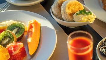 A breakfast setting with plates of fruit, a glass of orange juice, and a cup of coffee.