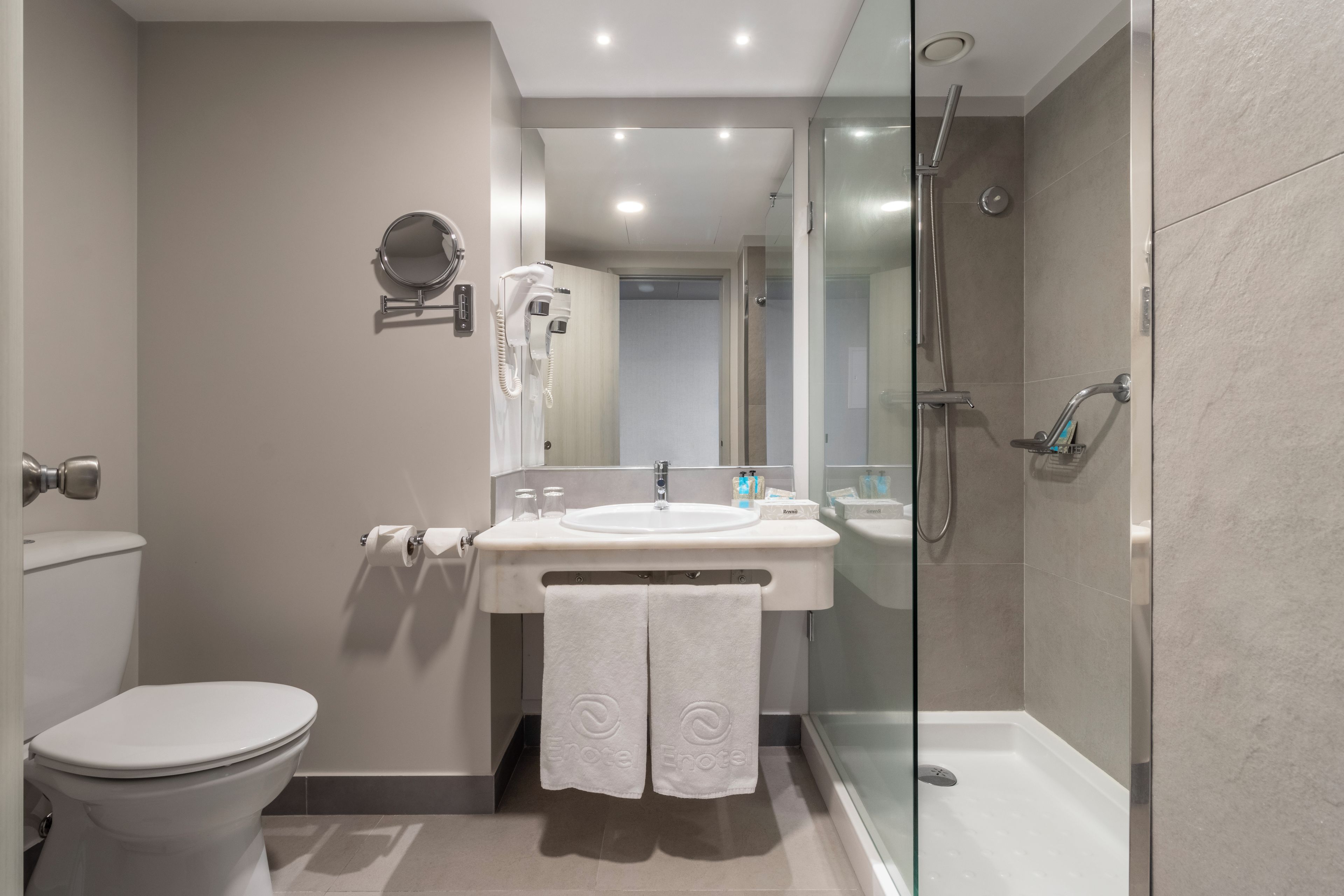 A modern bathroom with a toilet, sink, and glass-enclosed shower.