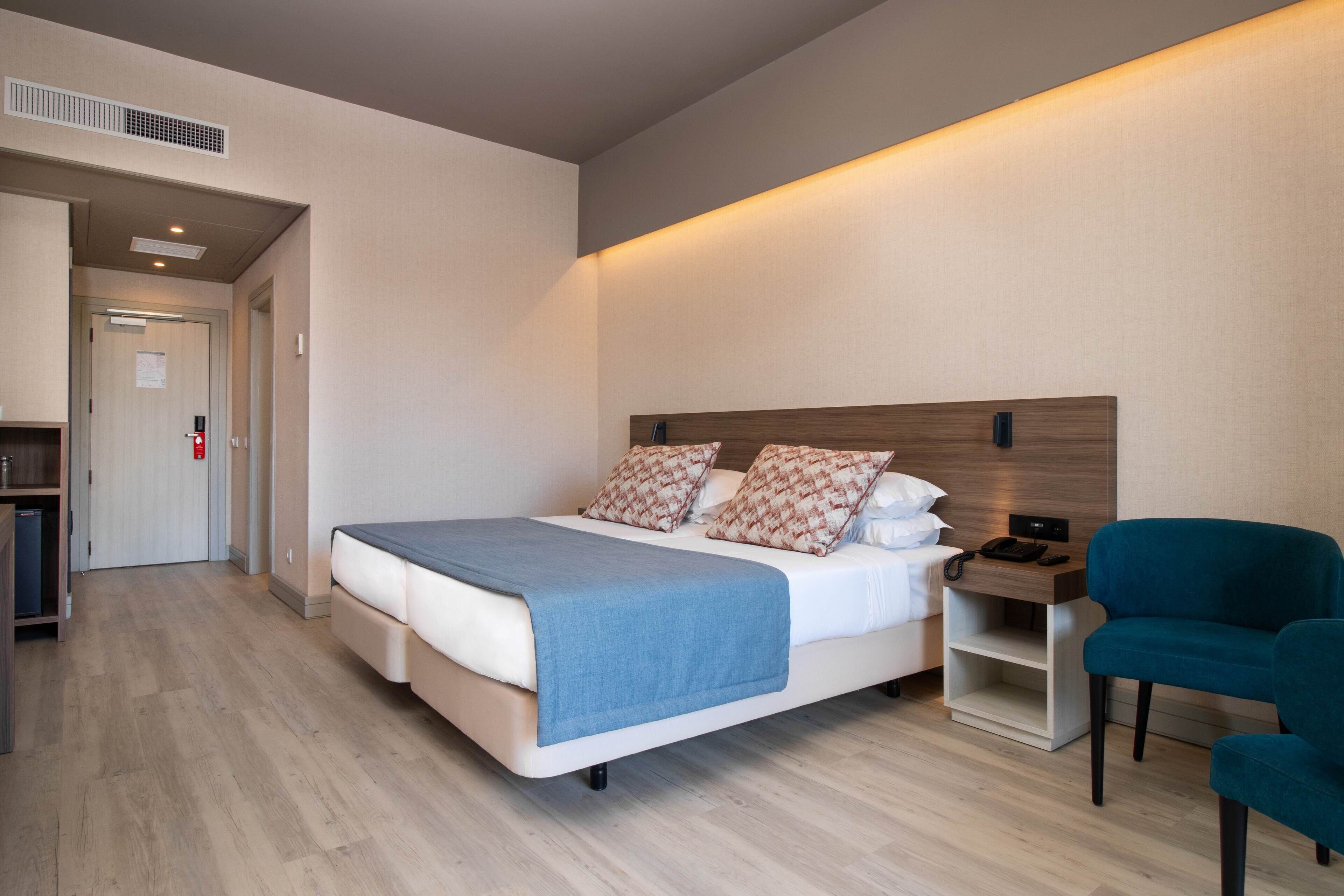 Quarto de hotel moderno com cama, mesa de cabeceira e uma cadeira.