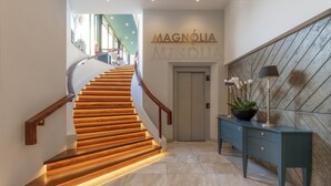 A modern hotel lobby with a wooden staircase, a reception desk, and a sign reading "Magnolia Manor." - Enotel Magnólia (Funchal)