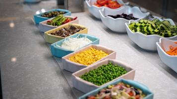 Un tavolo del buffet con diversi cibi esposti in ciotole.