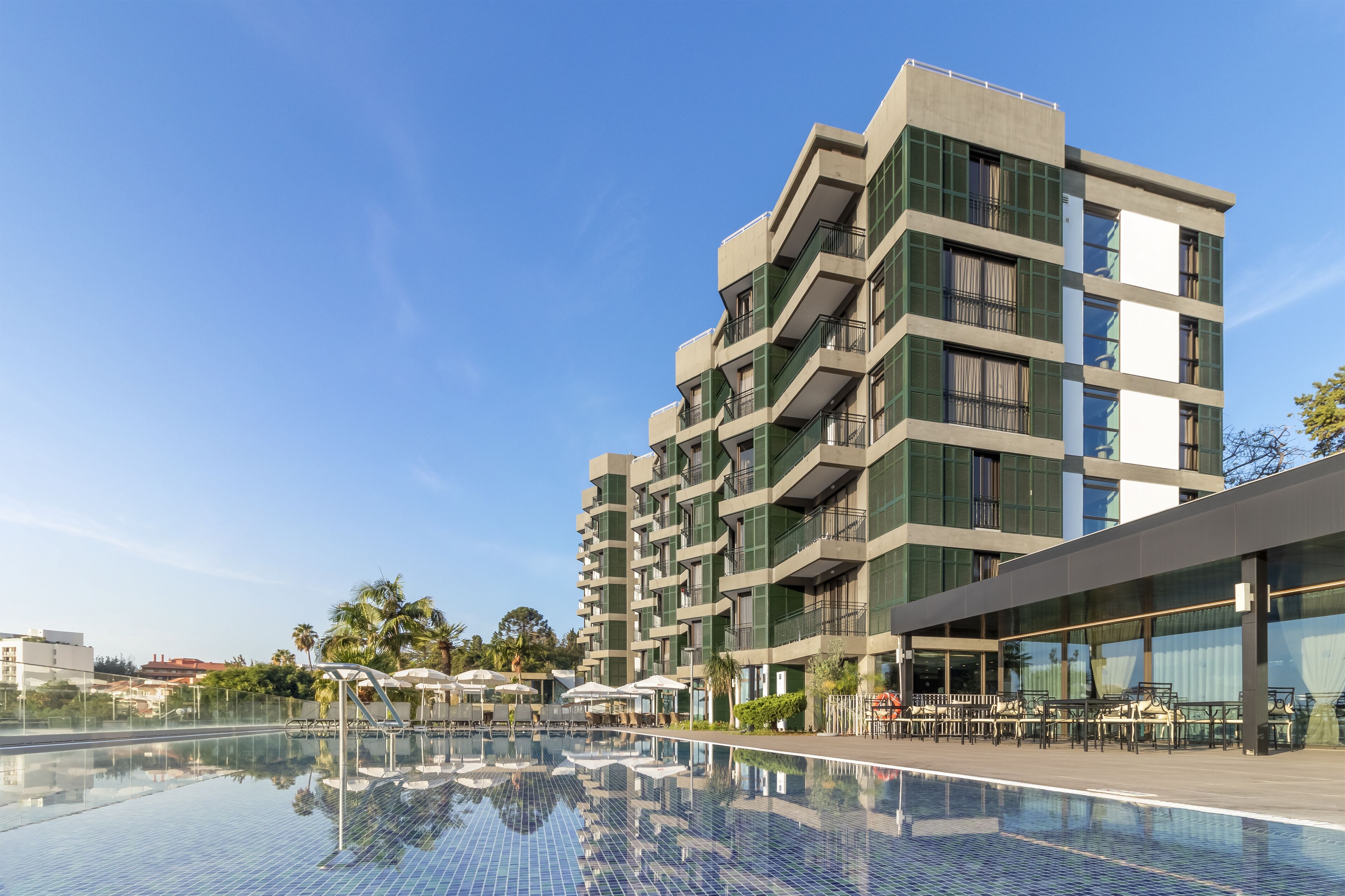 A modern hotel with a rooftop pool and outdoor seating area.
