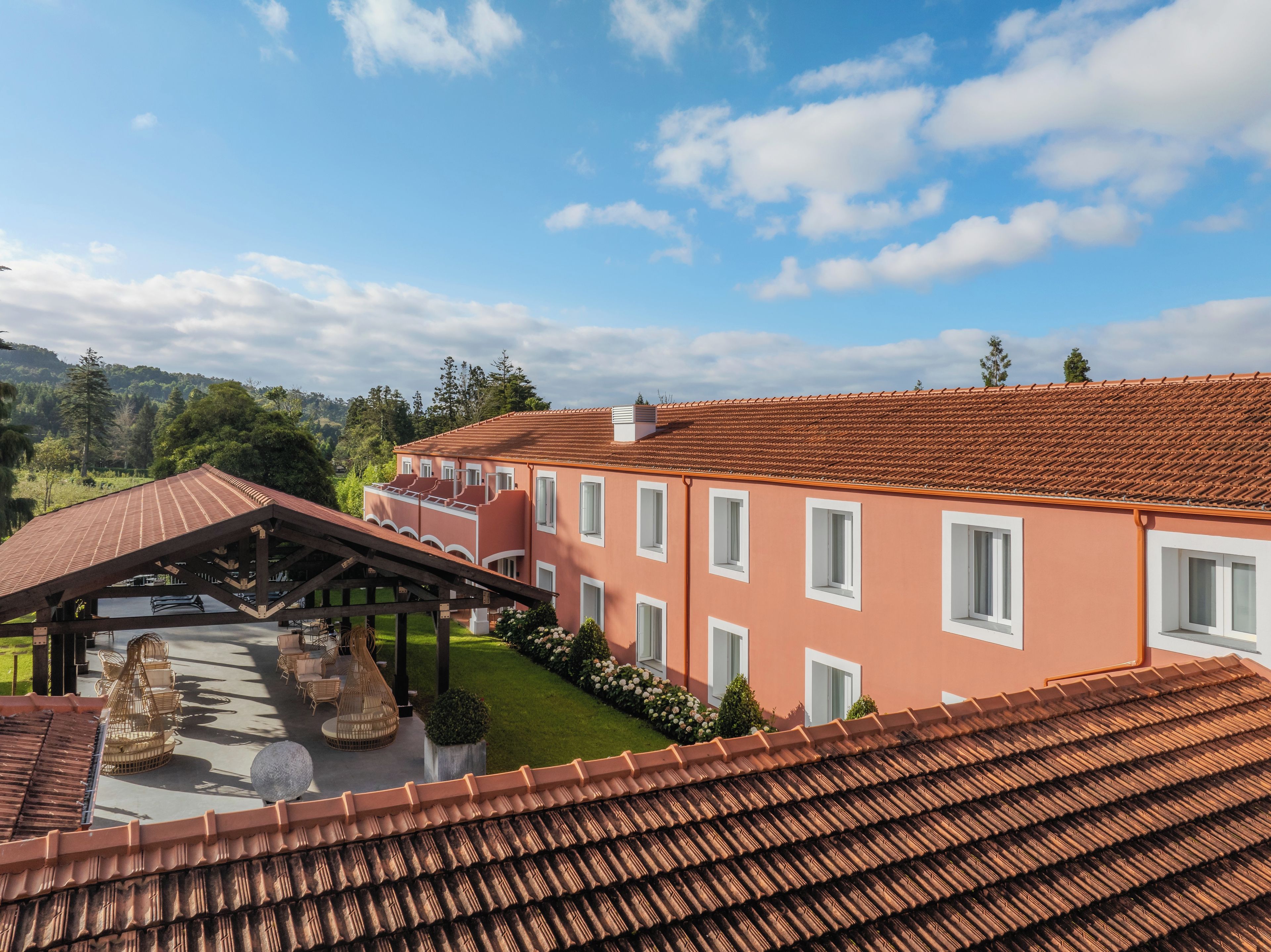 A multi-story building with a red-tiled roof, a covered patio area, and a well-maintained lawn.