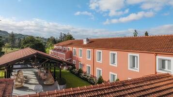 A multi-story building with a red-tiled roof, a covered patio area, and a well-maintained lawn.