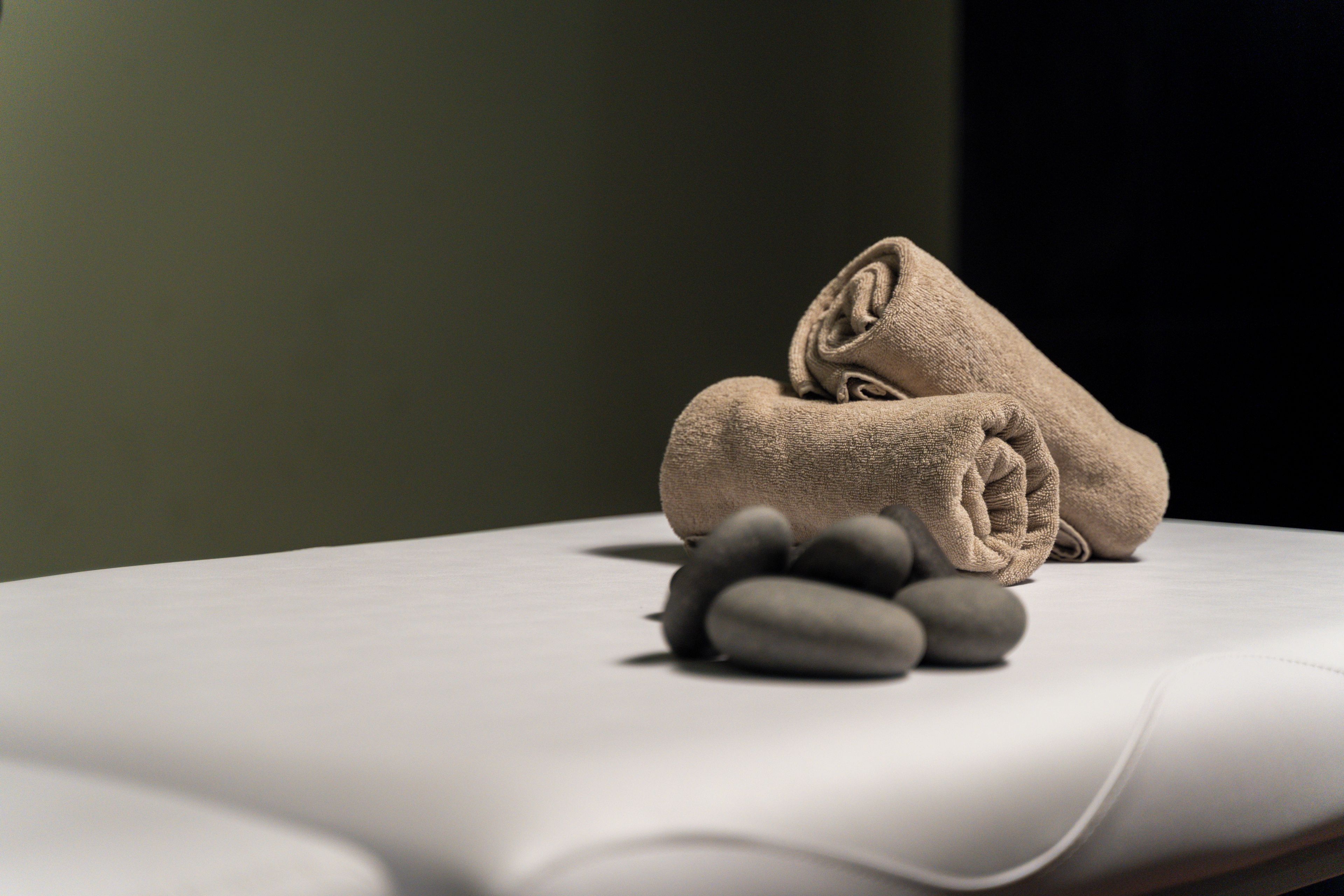 A neatly folded towel and smooth, unadorned surface, likely a bed or massage table, with a plain background.