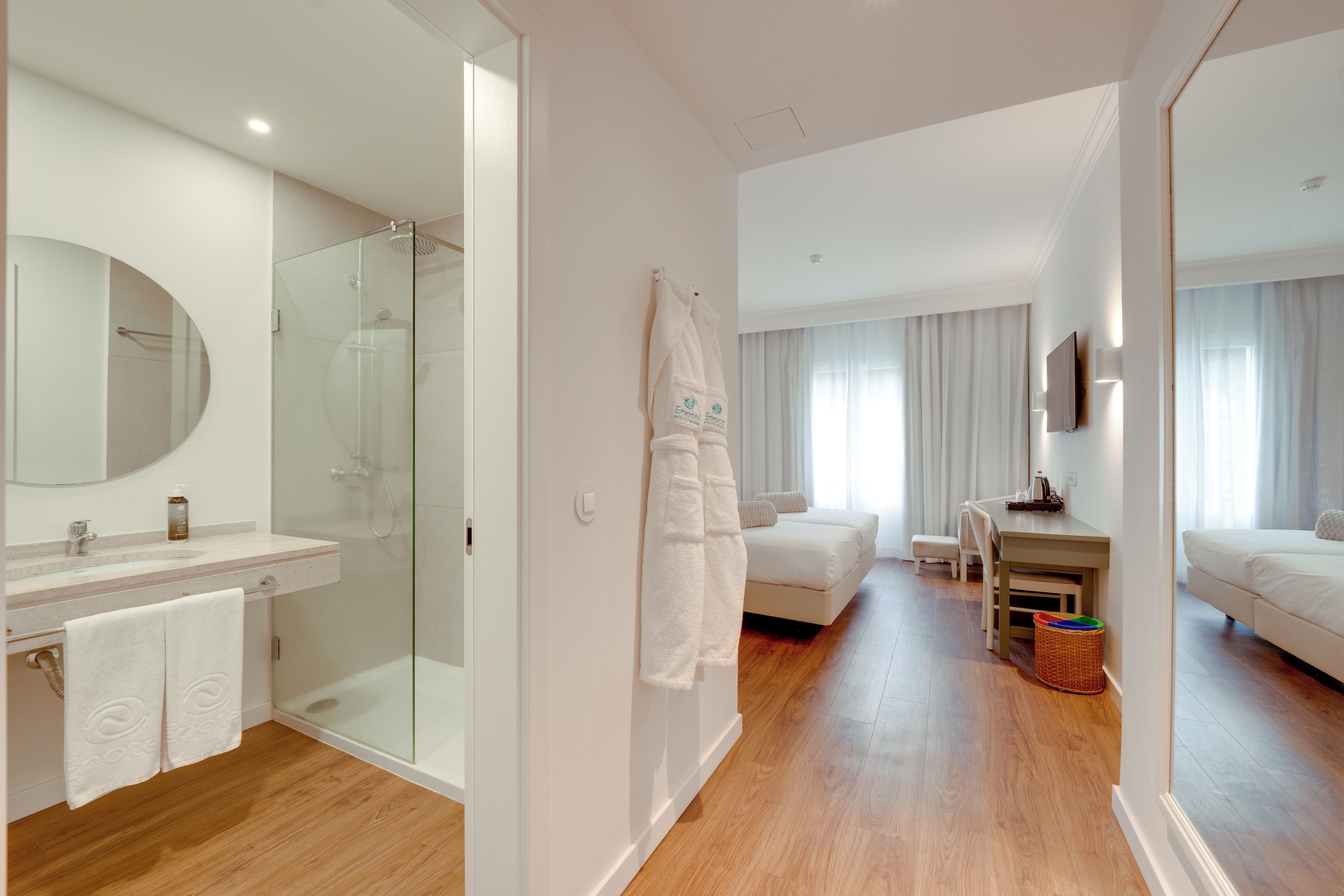 Habitación de hotel con ducha, cama, escritorio y televisión.