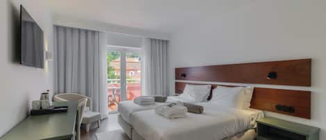 A modern hotel room with a bed, bedside table, and a desk with a chair.