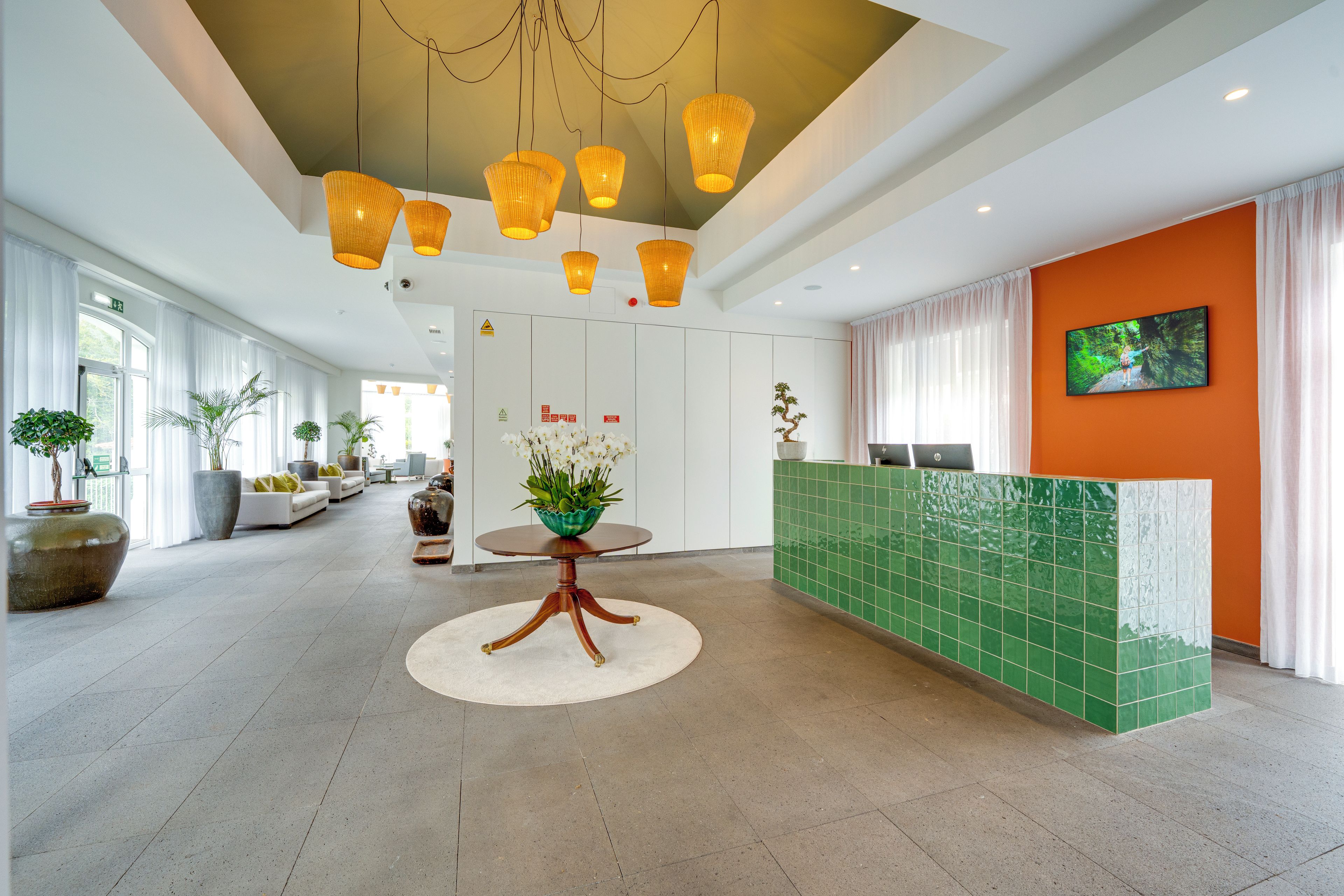A modern hotel lobby with a reception desk, seating area, and a large window.