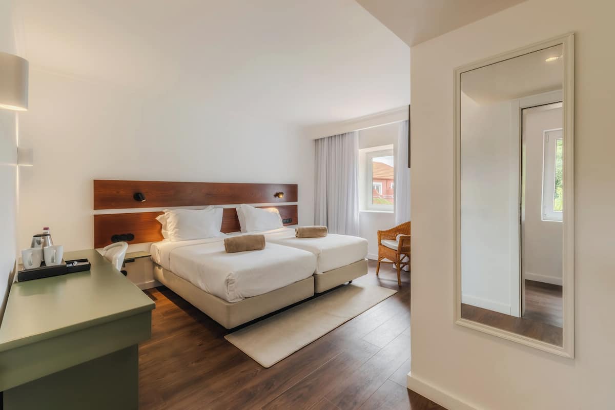 A hotel room with a bed, bedside table, and a chair.