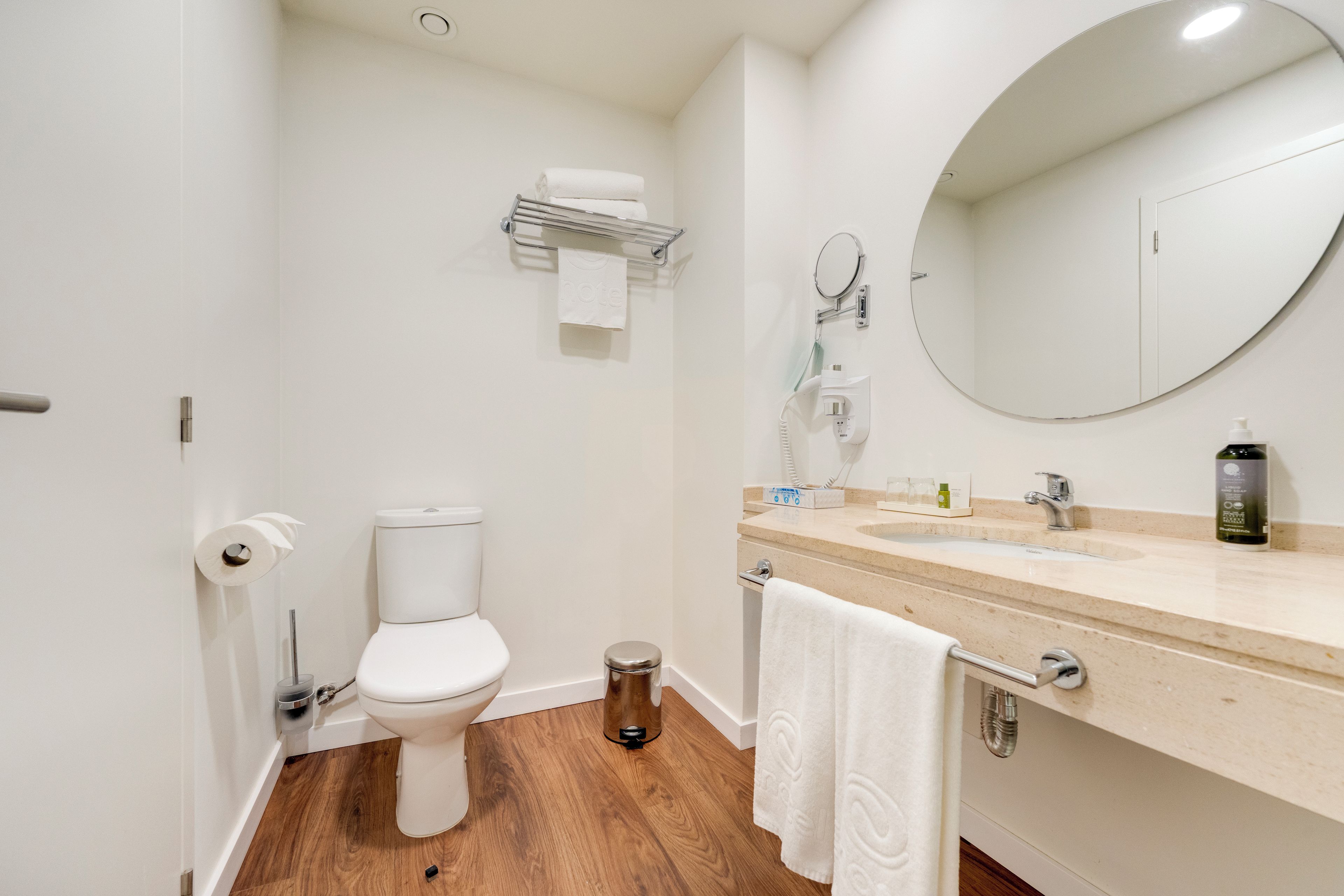 A small bathroom with a toilet, a sink, a mirror, and a towel rack.