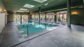 A swimming pool with sunlit skylights, lounge chairs, and a view of greenery outside. - Enotel Santo da Serra (Machico)