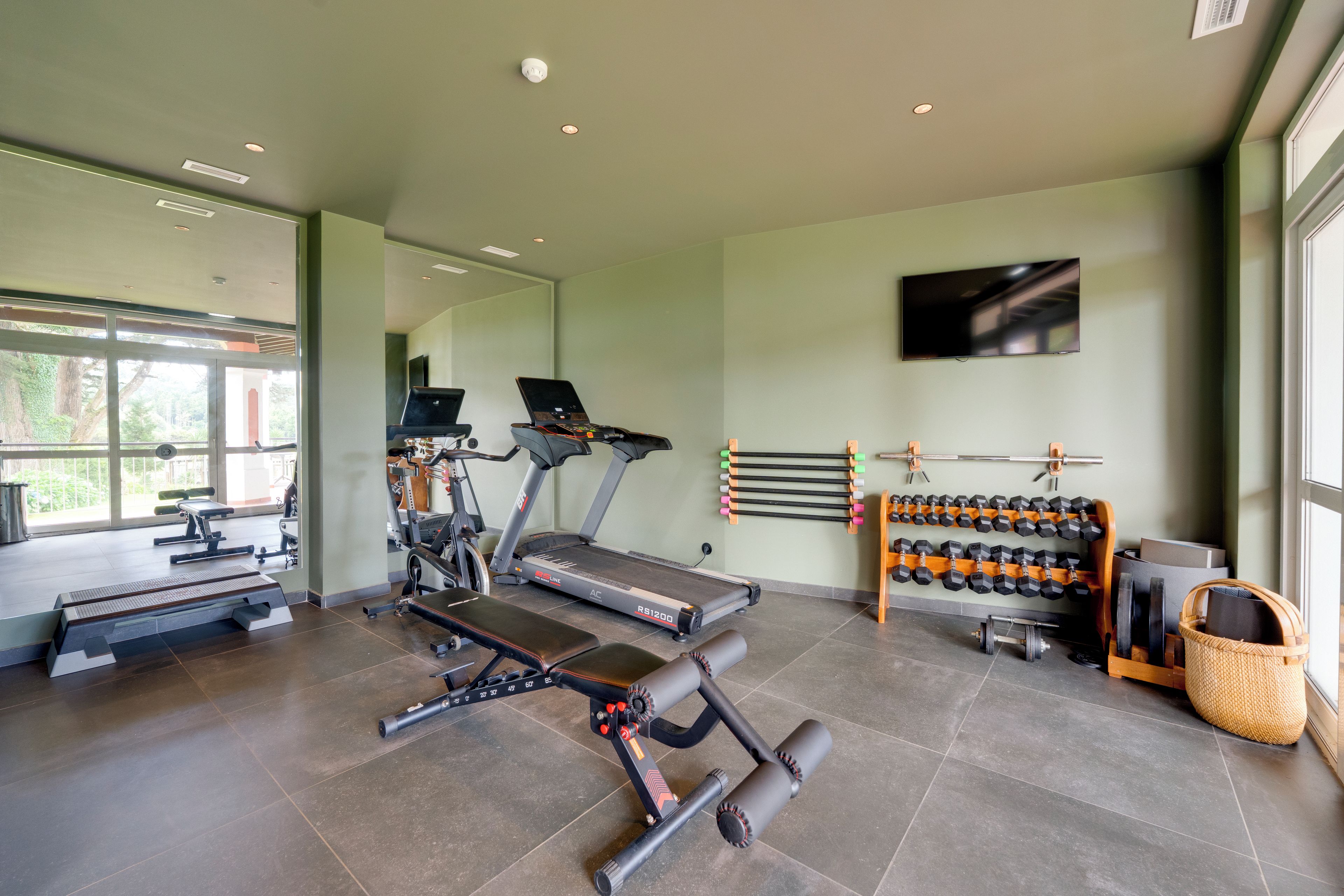 Una palestra con tapis roulant, panche pesi e manubri.