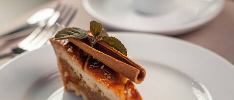 A slice of cake on a plate with a cup of coffee in the background.