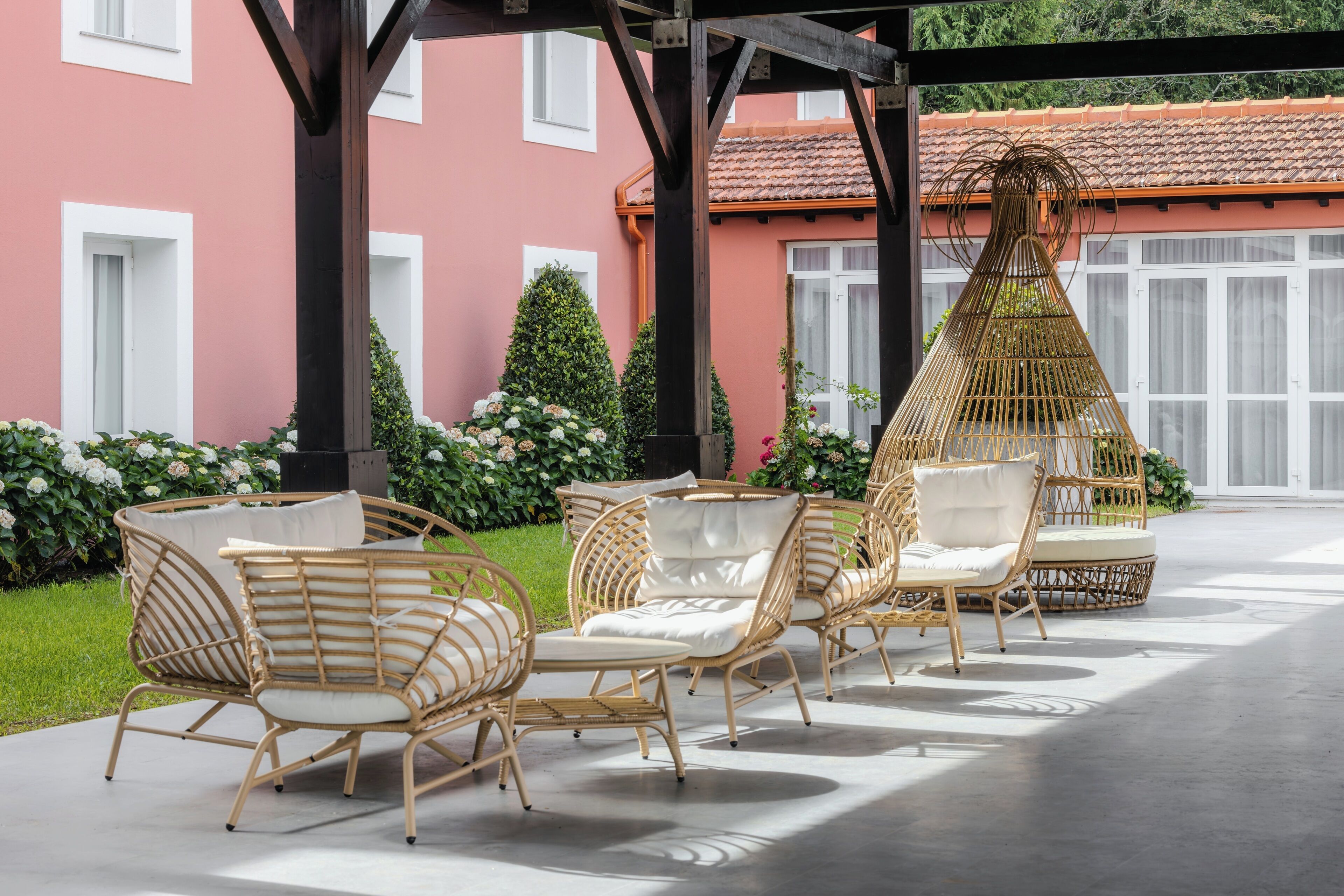 An outdoor seating area with wicker furniture and a decorative hanging chair.