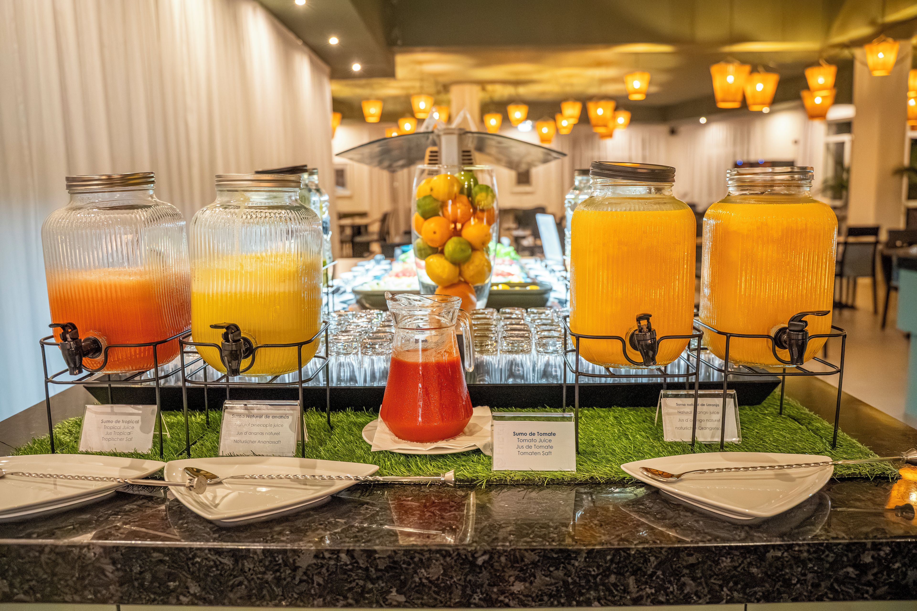 A buffet with various fruit juices and a tropical drink, with labels indicating the type of juice.