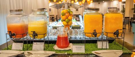A buffet with various fruit juices and a tropical drink, with labels indicating the type of juice.