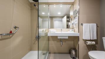 Un baño moderno con ducha acristalada, lavabo blanco y inodoro.