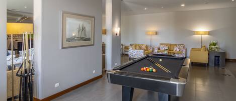 A pool table with balls, a framed picture, and a sofa with cushions.