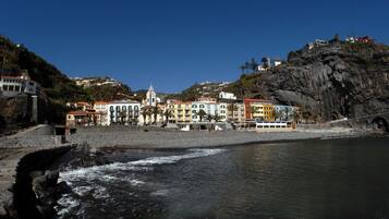 Un pueblo costero con edificios coloridos, un acantilado rocoso y un puente.