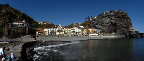A coastal town with colorful buildings, a rocky cliff, and a bridge.