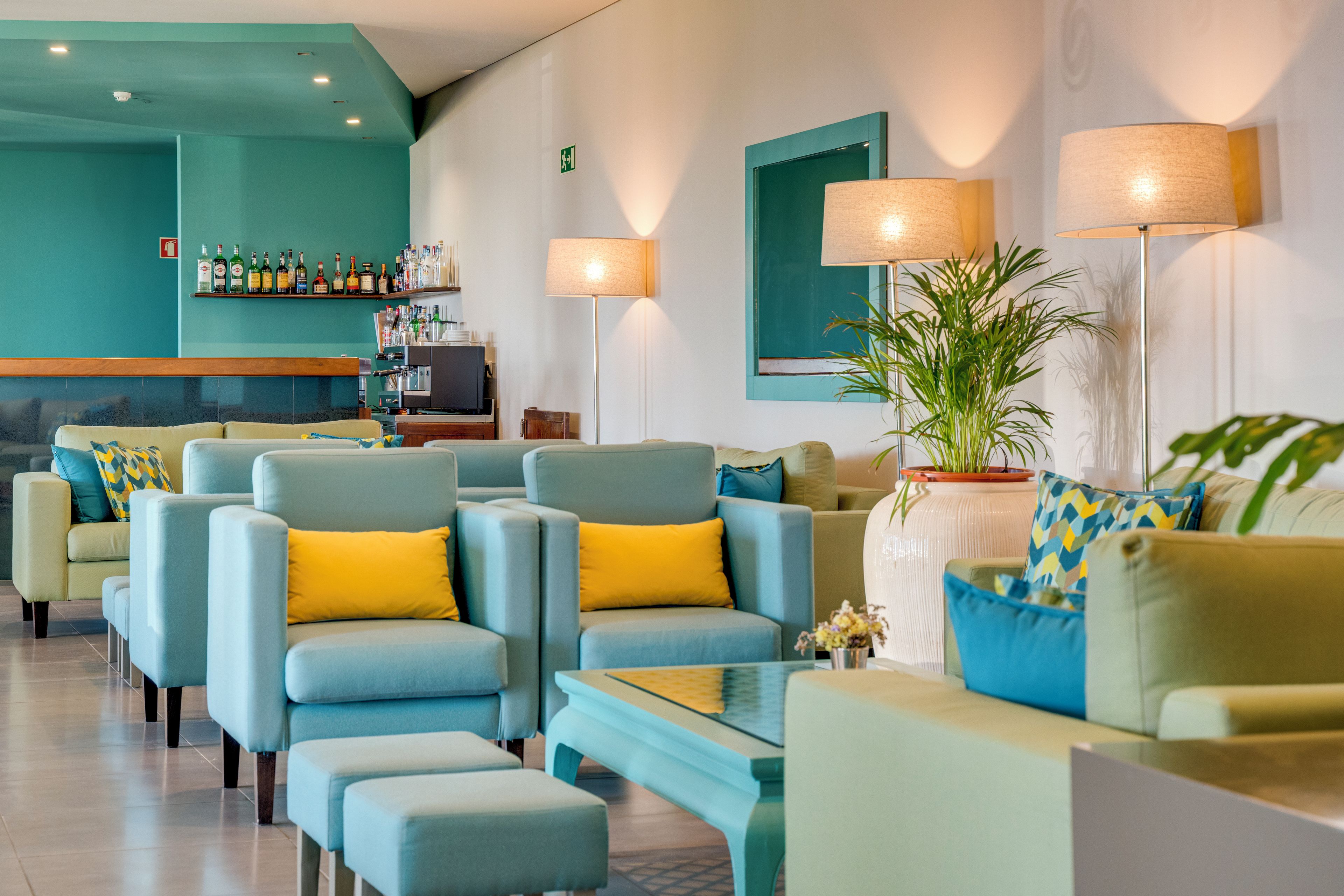 Un hall d’hôtel avec des espaces aménagés pour s’asseoir, un bar et un téléviseur.