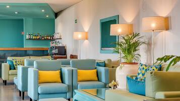 Un hall d’hôtel avec des espaces aménagés pour s’asseoir, un bar et un téléviseur.
