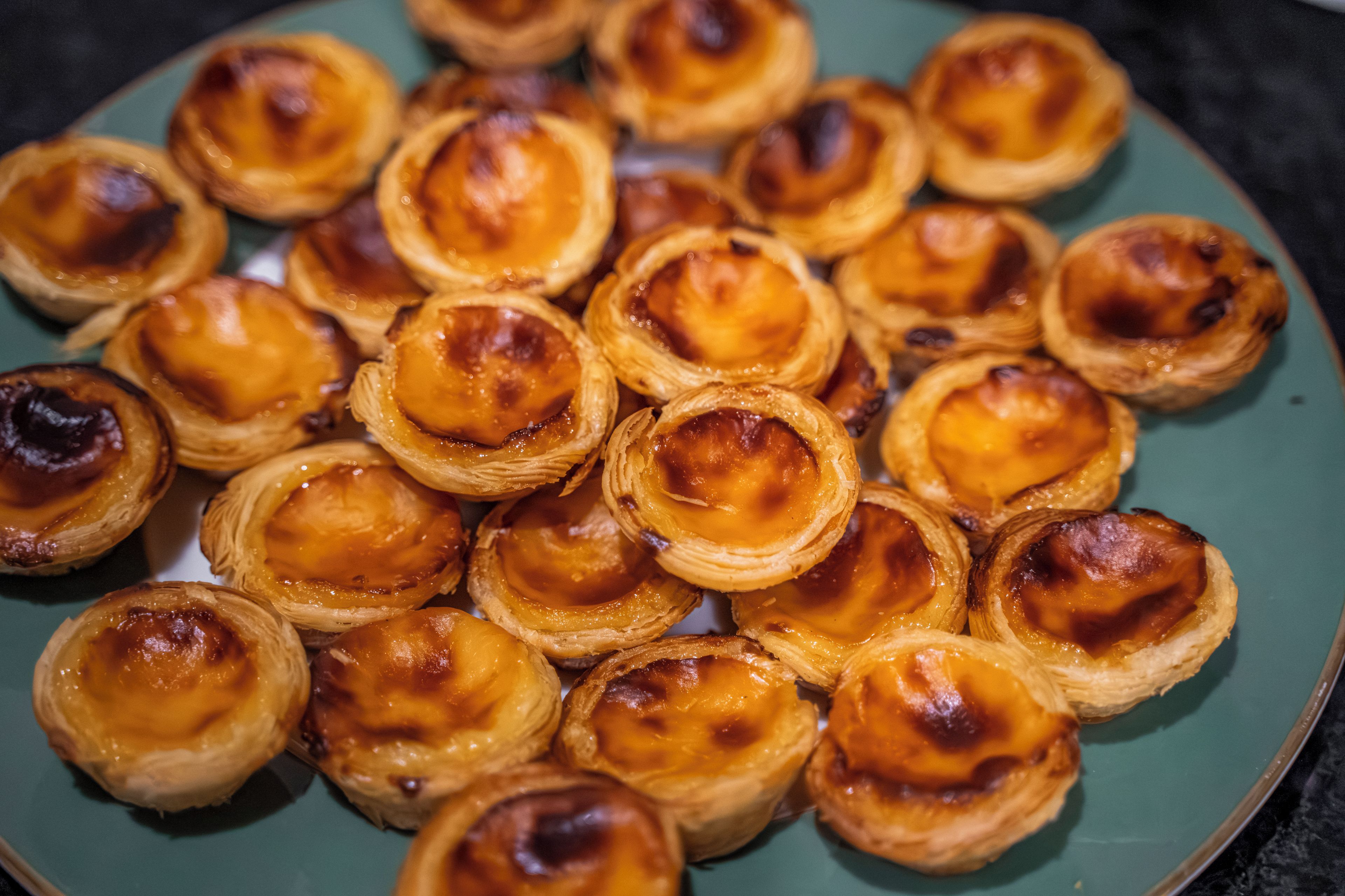 Een bordje met kleine, ronde gebakjes, met een goudbruine bovenkant, waarschijnlijk een soort taaltje.