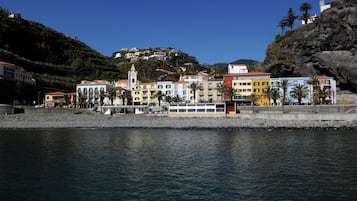 Uma cidade costeira com edifícios coloridos, um cais e uma colina com casas.