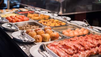 Un bufé con diversas opciones de comida, incluyendo frutas, pasteles y carnes.