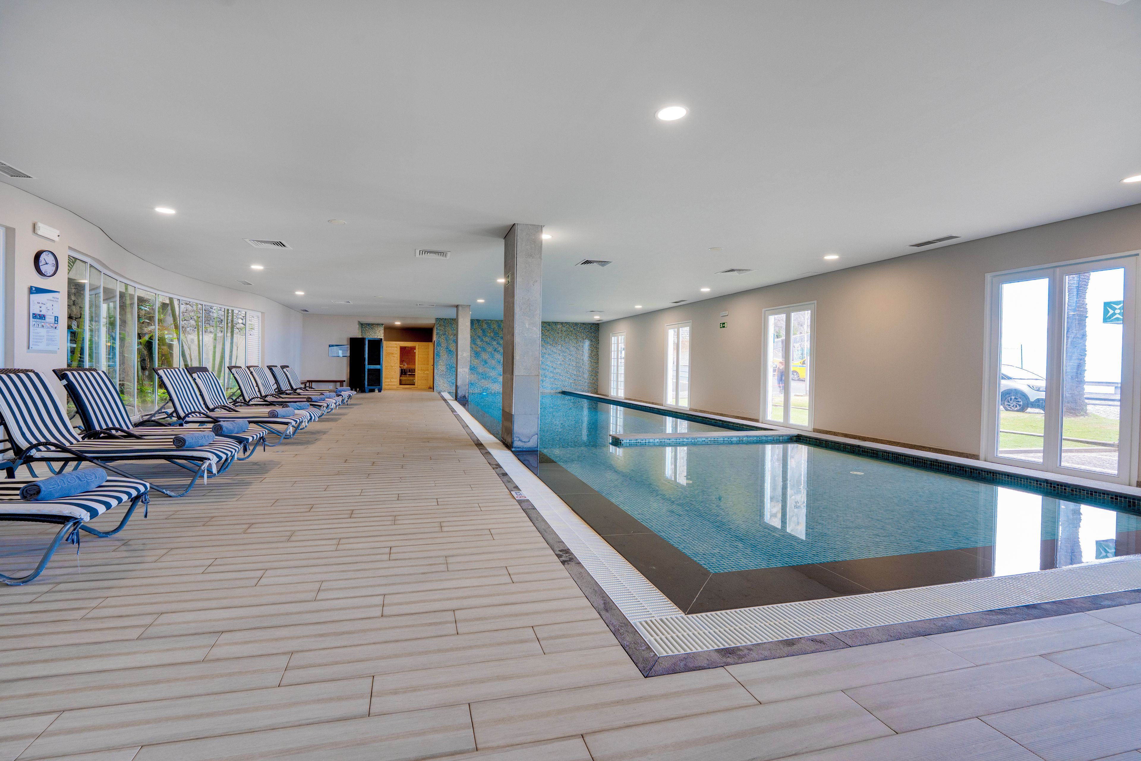 Une piscine avec des chaises longues et un sol carrelé.