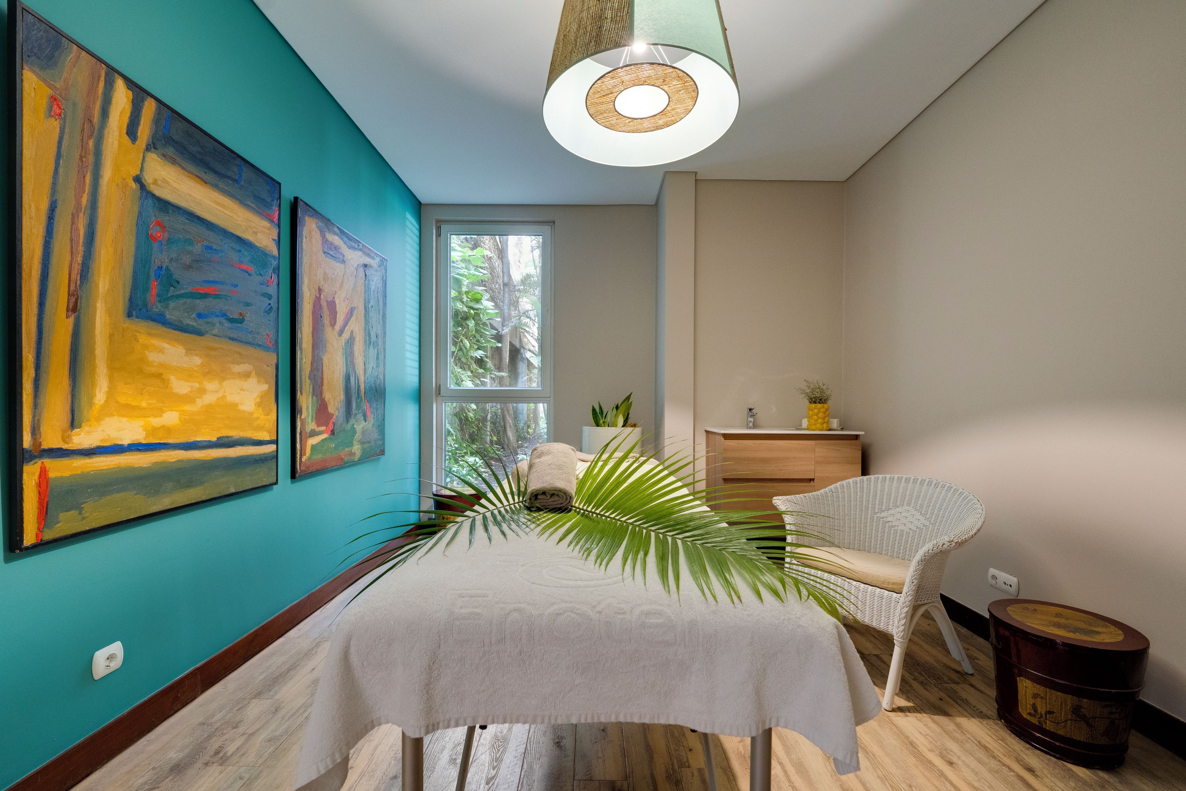 A room with a bed, a chair, a window, and two paintings on the wall.